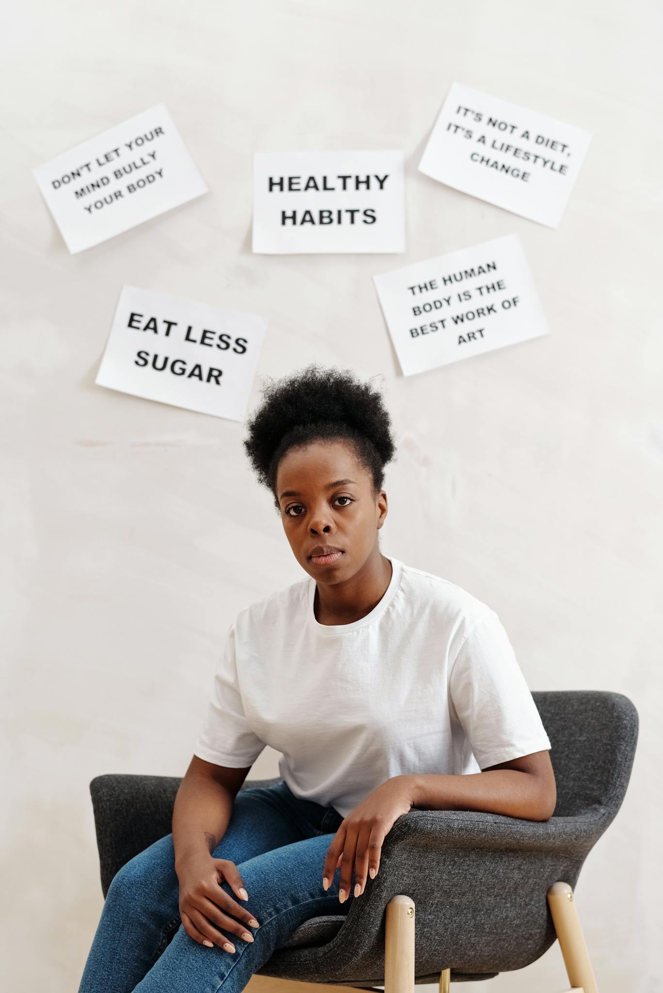 Young woman sitting in chair with motivational health posters behind her.